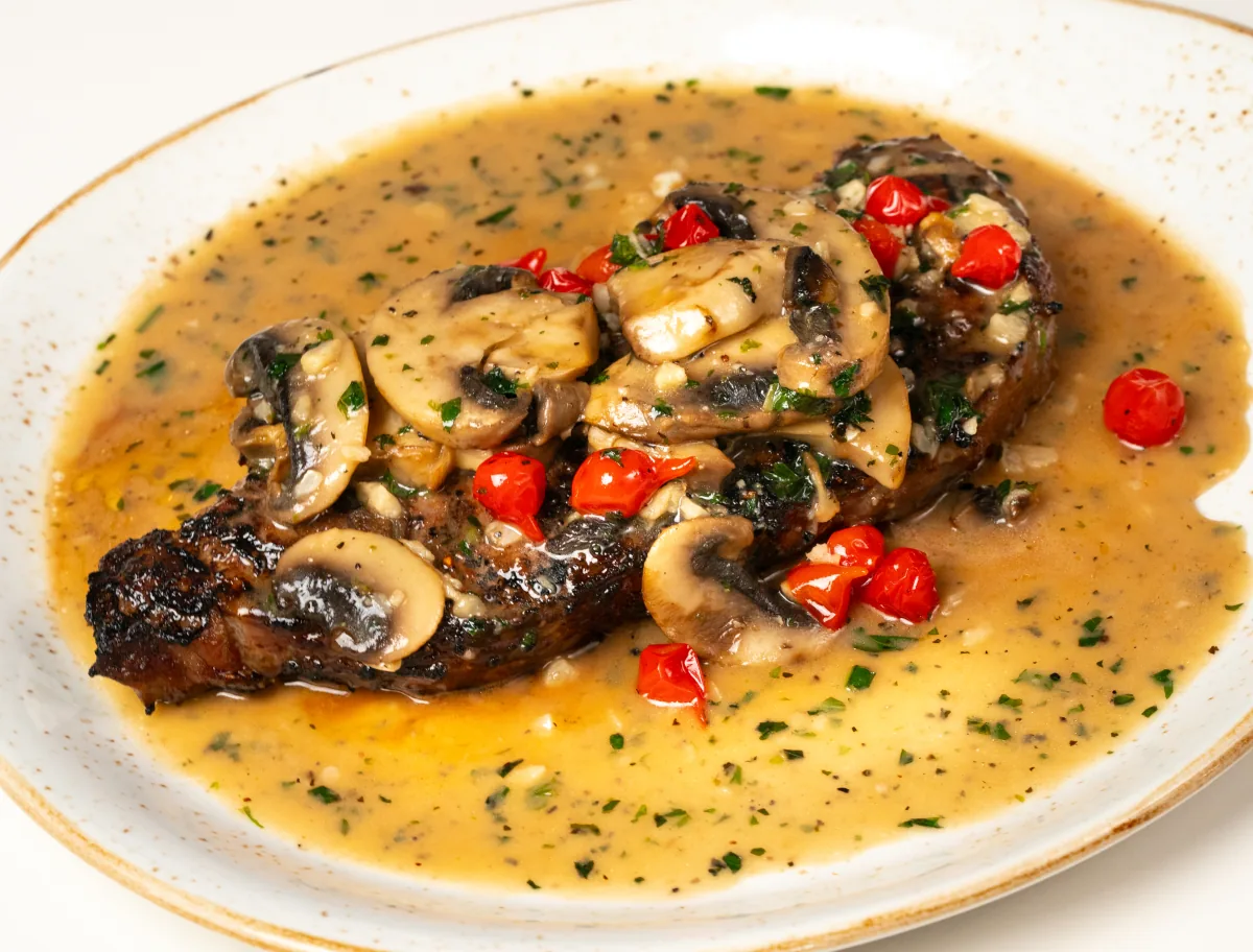Seared steak topped with mushrooms and sweet peppers